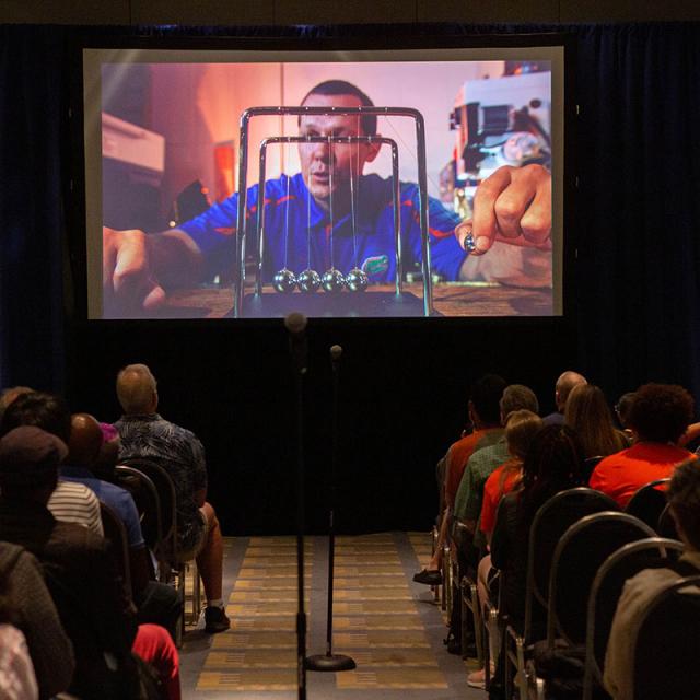 2019 Festival attendees watch a video on a projector screen